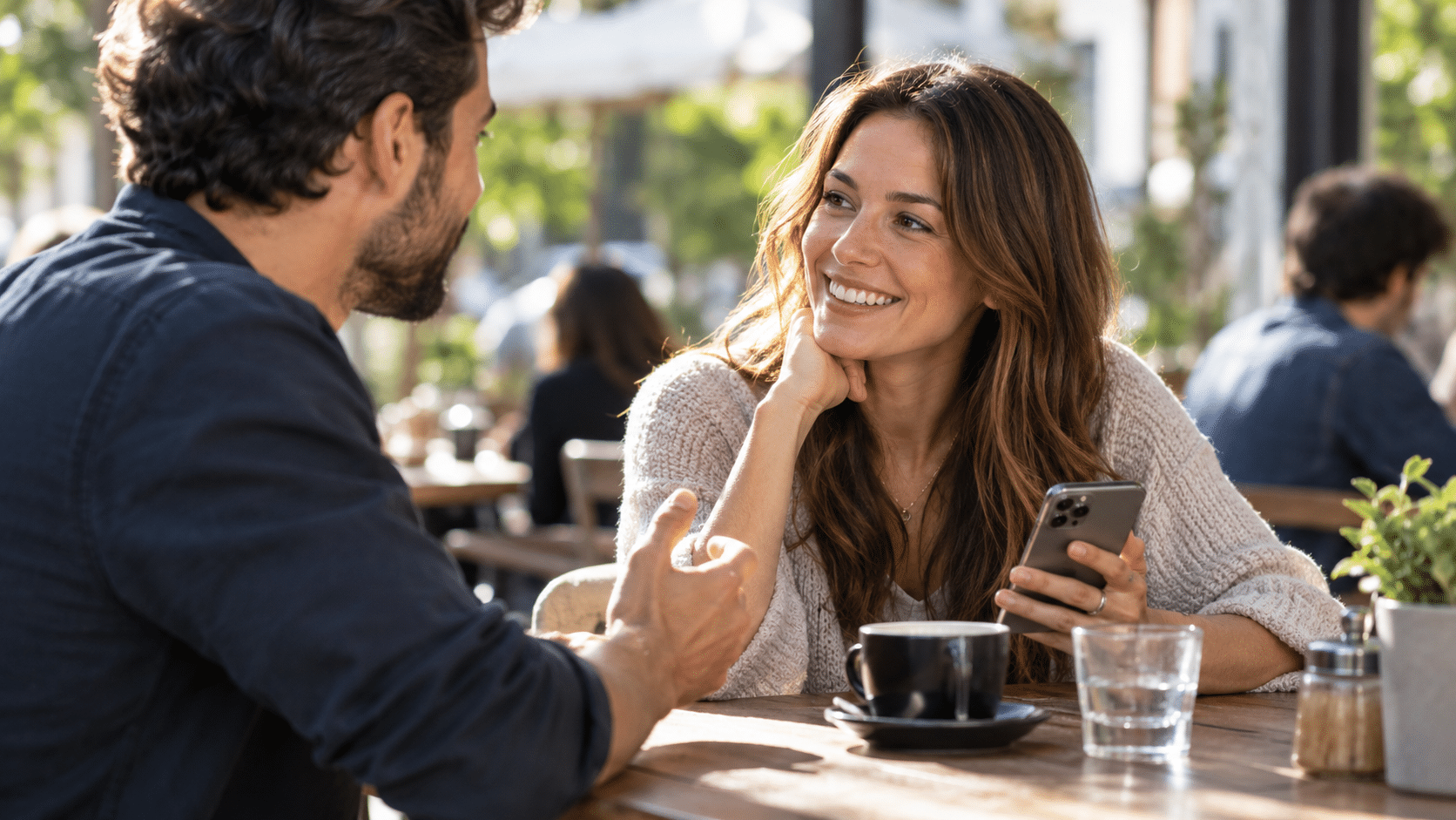 Two people talking face-to-face, one holding a smartphone with live captions during the conversation.
